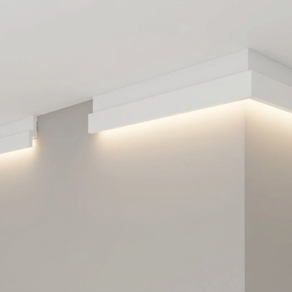Cornisa escalonada con luz LED realzada, muros gris cálido y cielo blanco